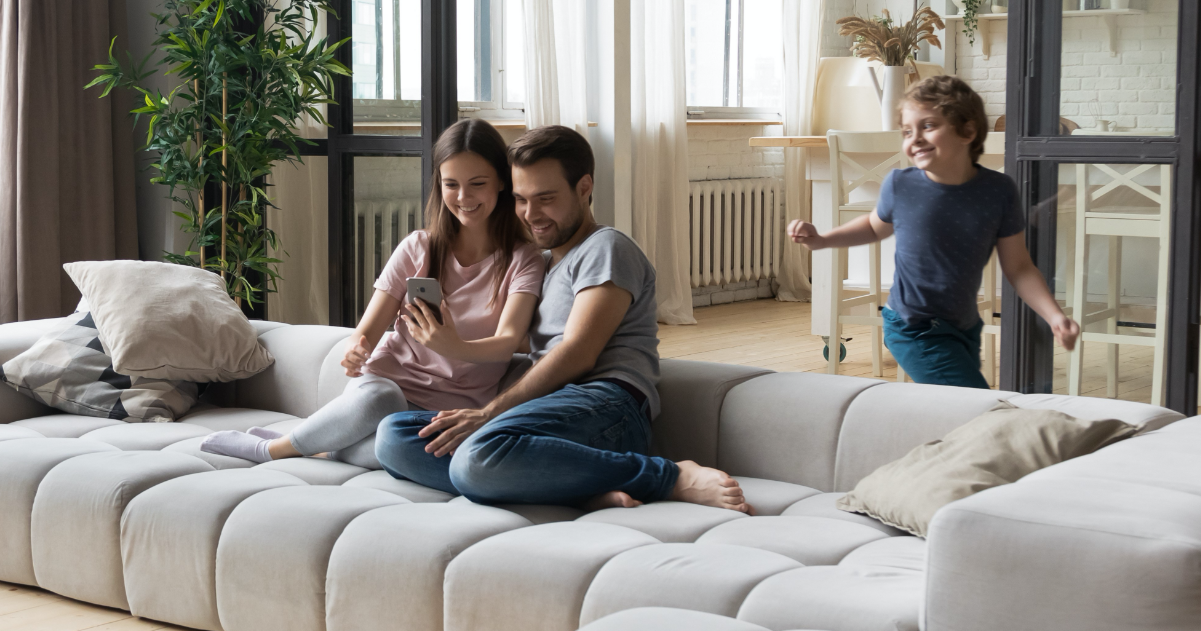 Une famille confortablement installée dans son salon utilise le monitoring de storelio sur son smartphone